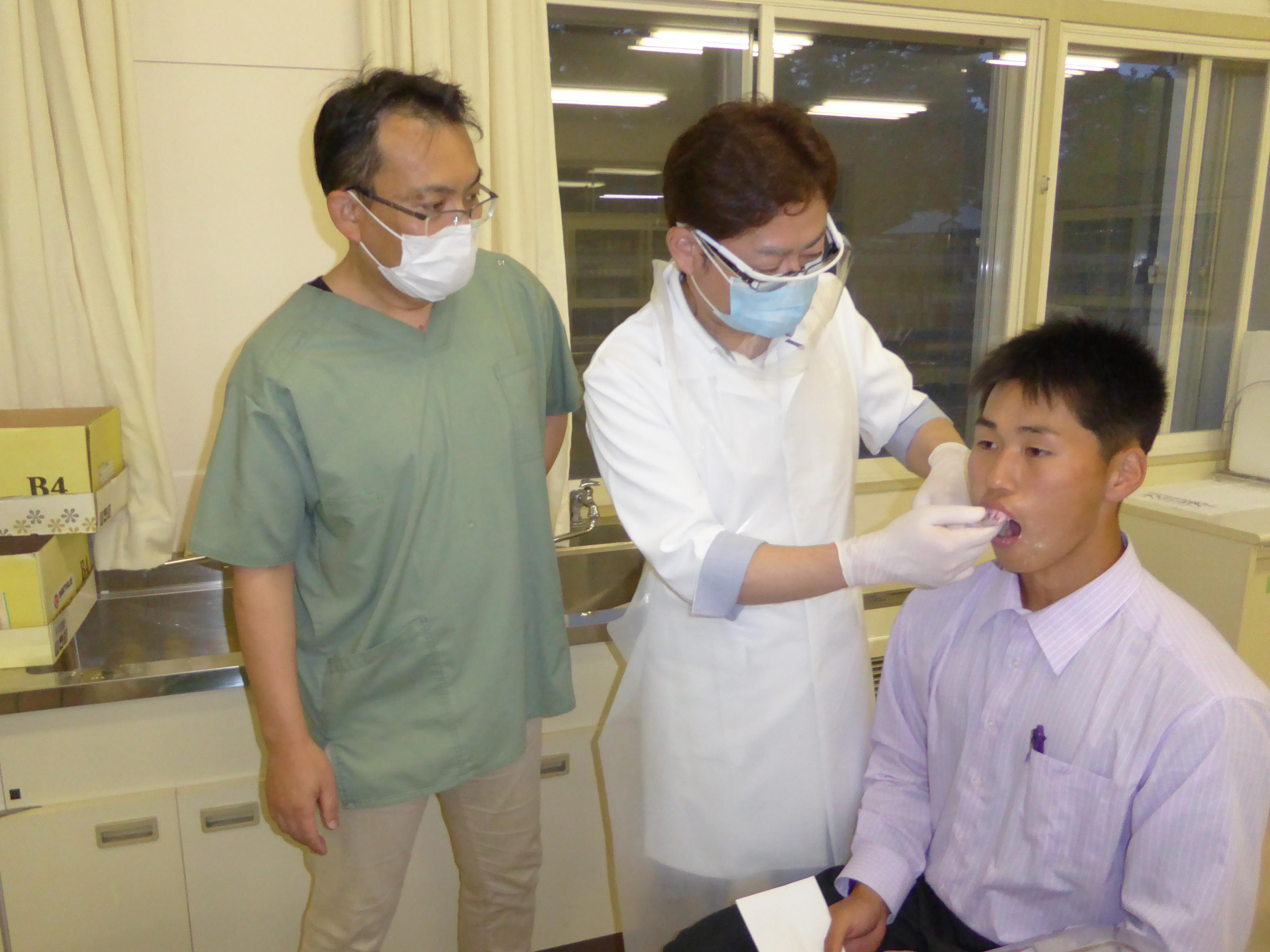 型どりを見守る鈴木俊一医師（左）。 