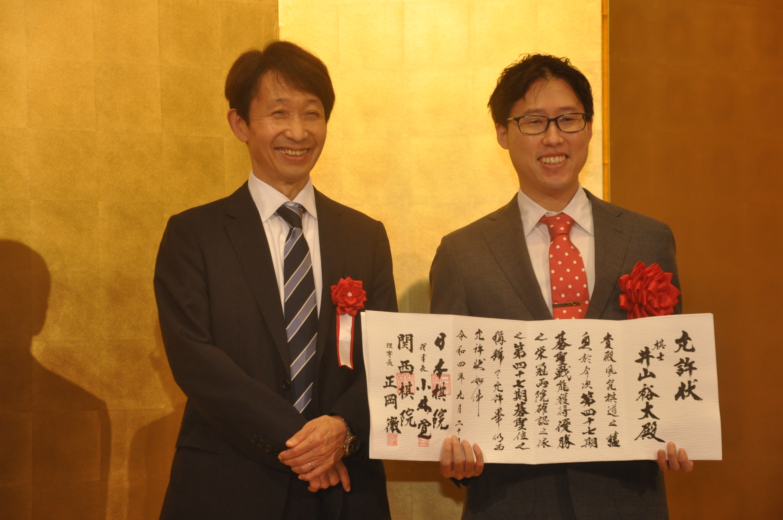 日本棋院の小林覚理事長から允許状を贈られた井山裕太碁聖（右）。