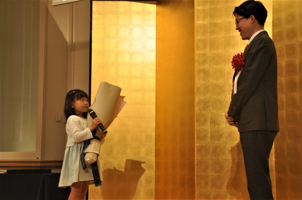 井山裕太碁聖（右）に花束を渡したファンの島倉佑奈ちゃん＝東京都港区の第一ホテル。