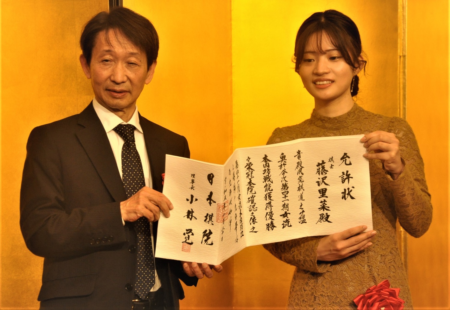 藤沢里菜女流本因坊に允許状を手渡した日本棋院の小林覚理事長（左）