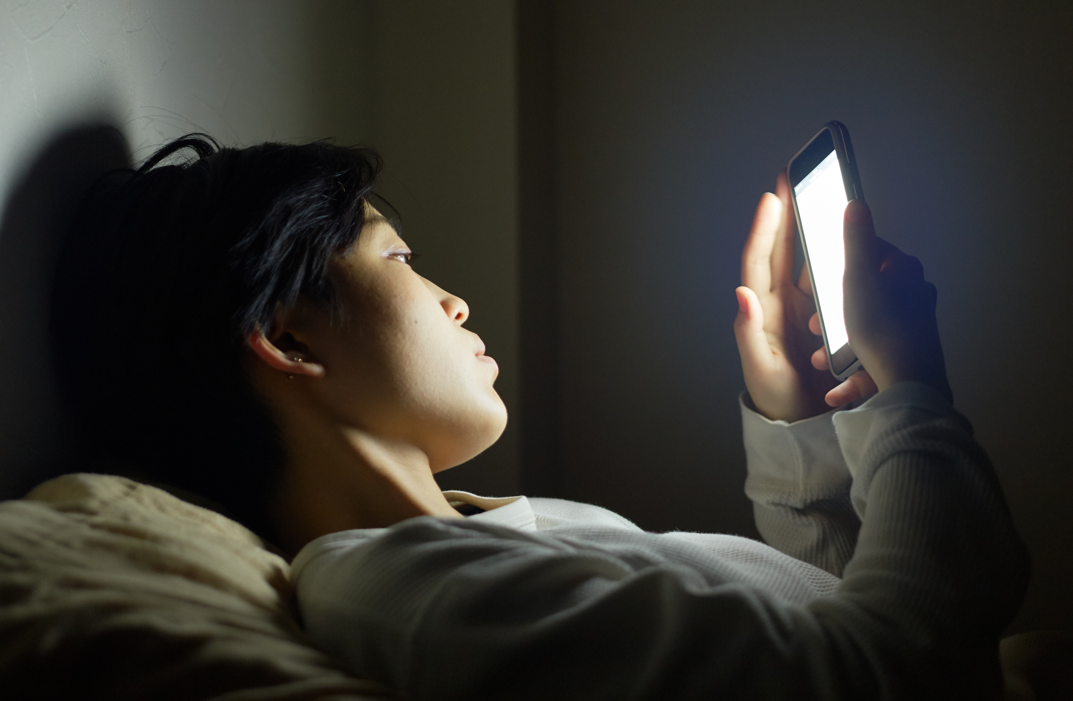 young woman fiddling her smartphone before bed