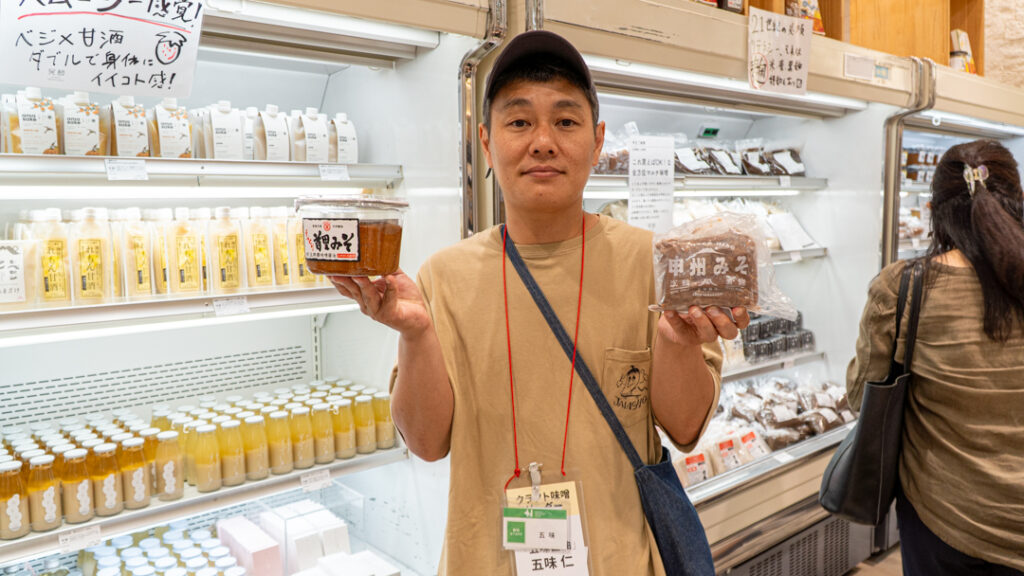 山梨県の五味醤油の五味仁さん。沖縄県の玉那覇味噌醤油の「首里みそ」（左）と五味醤油の「甲州みそ」