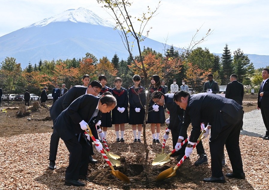 富士山を望む「世界の森やまなし」でフジザクラの苗木を植える長崎幸太郎山梨県知事（右）ら