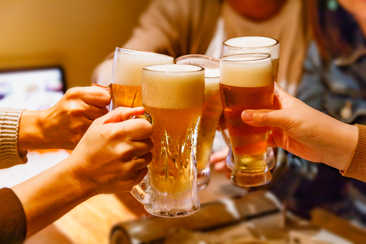 Hands and mug beer of many people toasting at a tavern