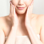 Skin care image of a beautiful young Asian woman putting her hand on her cheek